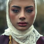 A woman is wearing a headscarf, looking sad.